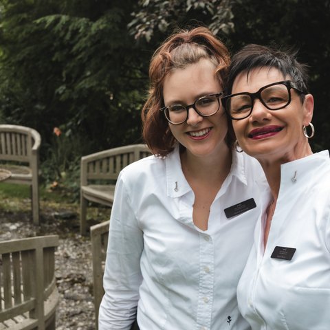 Gasthof Parsberg: Ein Gruß an den guten Geschmack Zwei lächelnde Frauen in weißen Uniformen mit Namensschildern im Garten