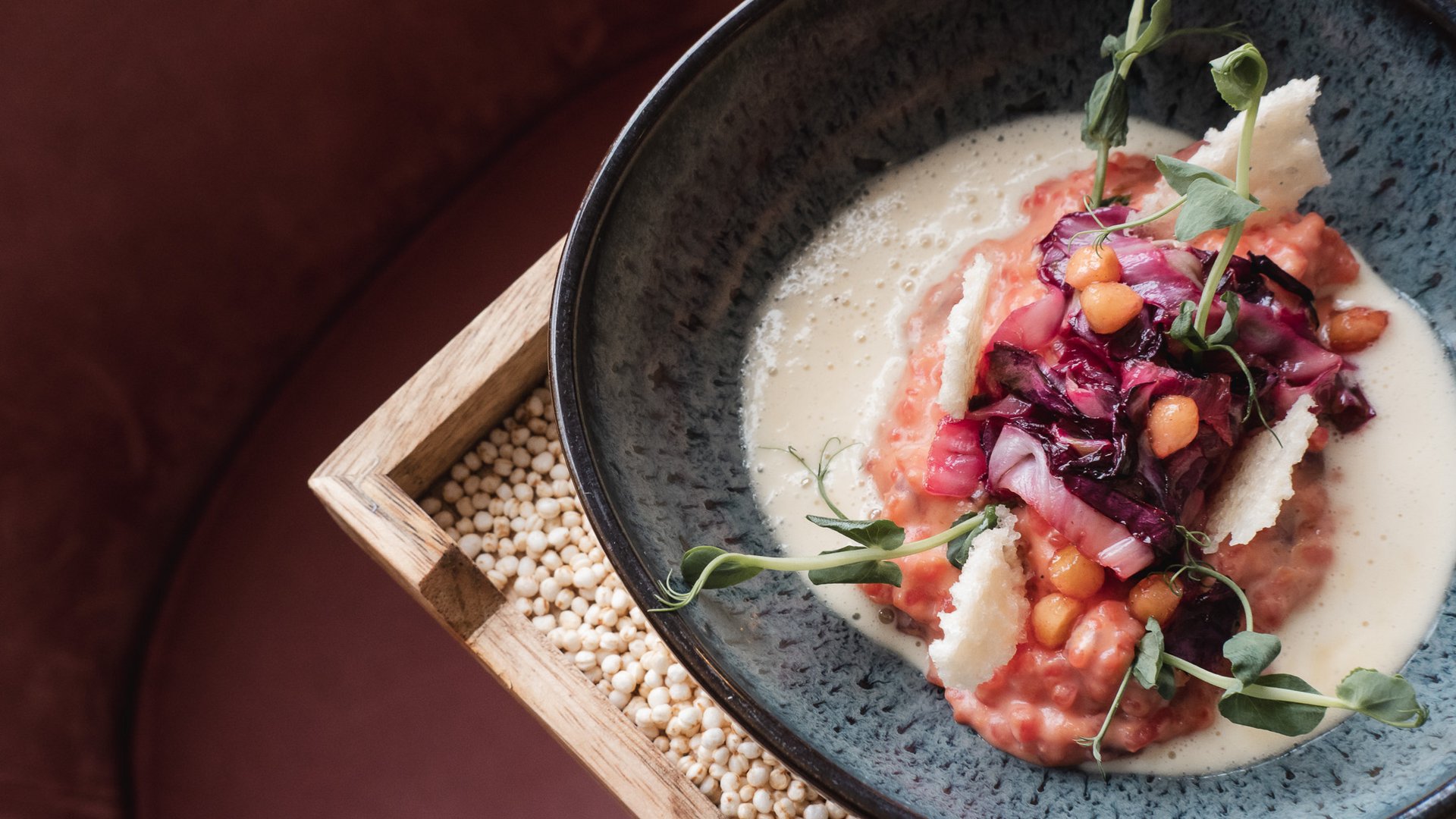 Hotel Oberpfalz: Urlaubsluft schnuppern! Elegantes Gericht mit Kichererbsen, Rotkohl, Käsestücken und Kräutern auf Teller