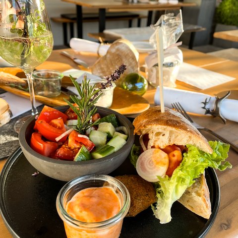 Beer garden in Parsberg: HirschenBlobb Plate with sandwich, salad, and dip in a restaurant with natural light