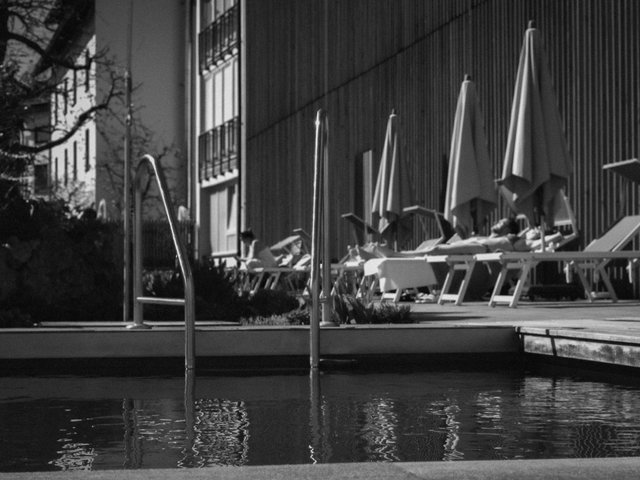 Romantik Hotel Hirschen: Bildergalerie Personen entspannen auf Liegestühlen neben einem Pool mit Sonnenschirmen