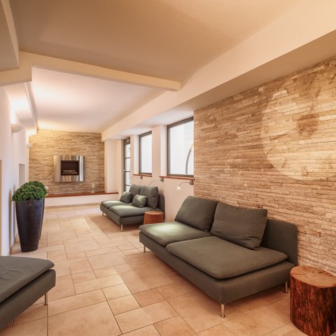 Day wellness in Upper Palatinate Modern waiting room with gray sofas and stone wall with fireplace