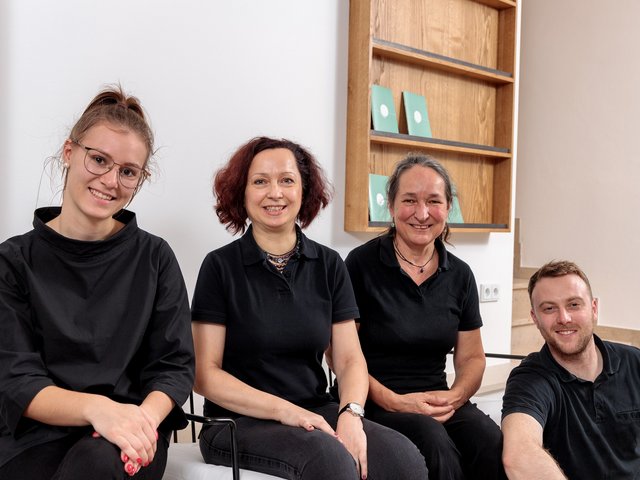 Romantik Hotel Hirschen: picture gallery Four smiling people in black clothing sitting in front of a bookshelf