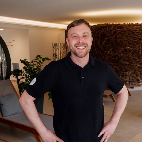 Tageswellness in der Oberpfalz Lächelnder Mann im schwarzen Poloshirt steht in modern eingerichteten Innenraum