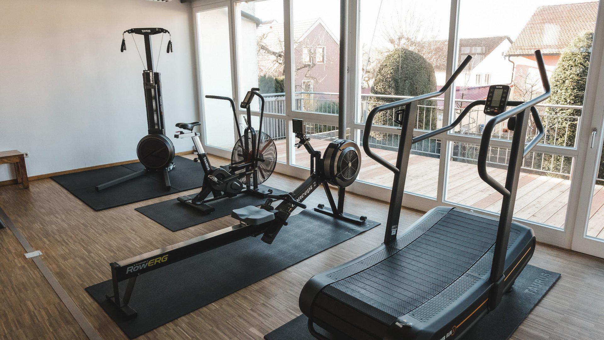 Fitnessraum Gym room with rowing machine, treadmill, bike, and training equipment by large windows