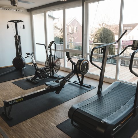 Fitnessraum Gym room with rowing machine, treadmill, bike, and training equipment by large windows