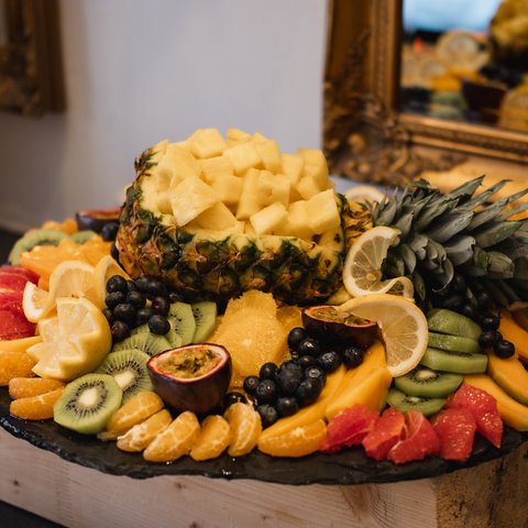 Brunch - das Langschläferfrühstück Buntes Obstarrangement mit Ananas, Kiwi, Orange und Passionsfrucht auf schwarzer Platte