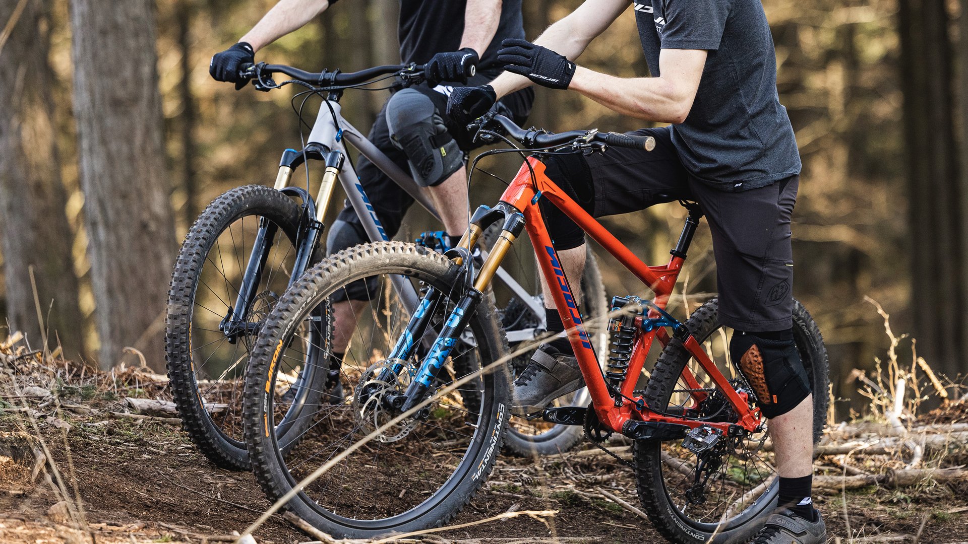 Looking for a hotel with bike rental in Bavaria? Two mountain bikers standing with their bikes in the forest wearing protective gear