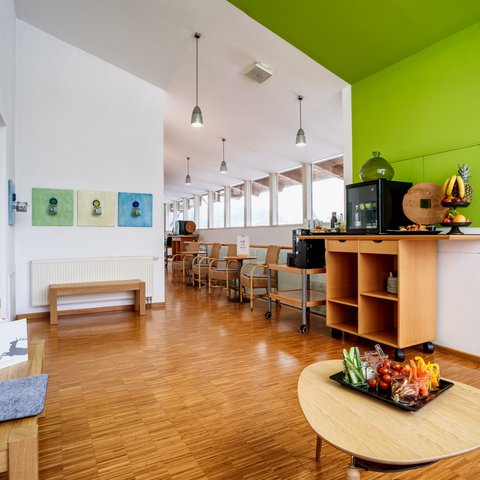 Looking for somewhere for conferences in Bavaria? Bright waiting area with chairs, table, and snack bar with fruit and vegetables