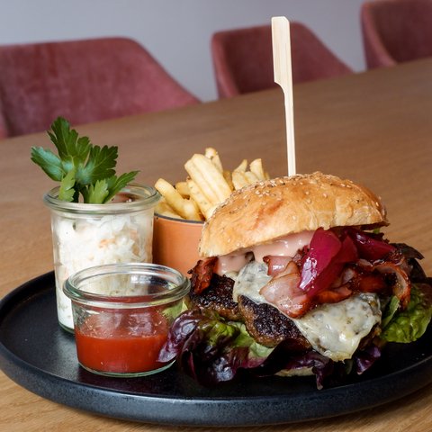 Kulinarik & Genuss in der Oberpfalz Burger mit Speck, Käse, Pommes, Krautsalat und Ketchup auf schwarzem Teller