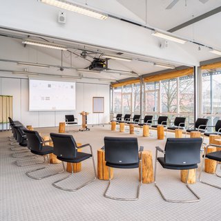 Leistungen und Preise für Tagungen und Konferenzen Großer heller Konferenzraum mit Stühlen im Kreis und Holzscheiben als Tische