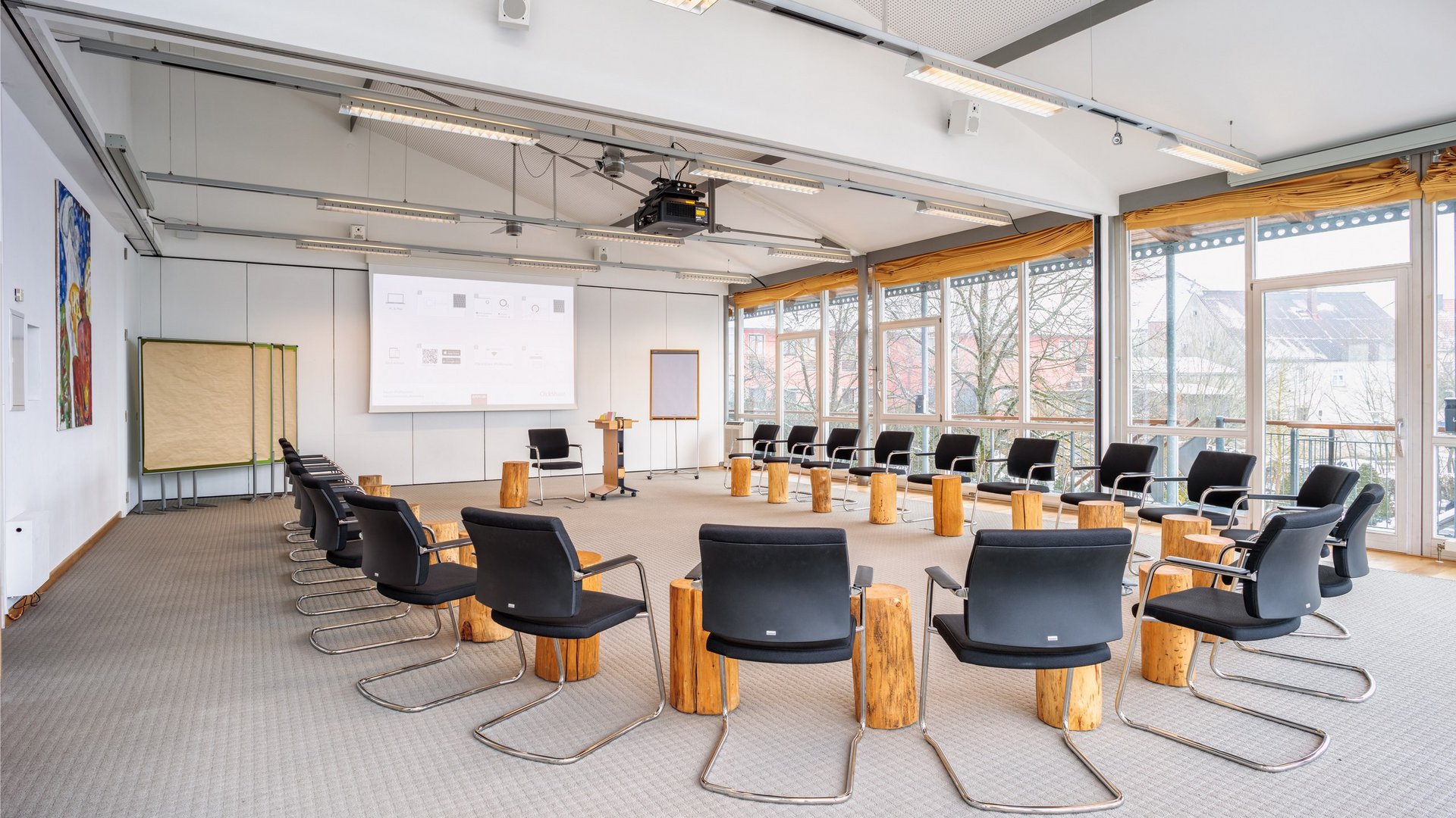 Large bright conference room with chairs in a circle and wooden stools as tables