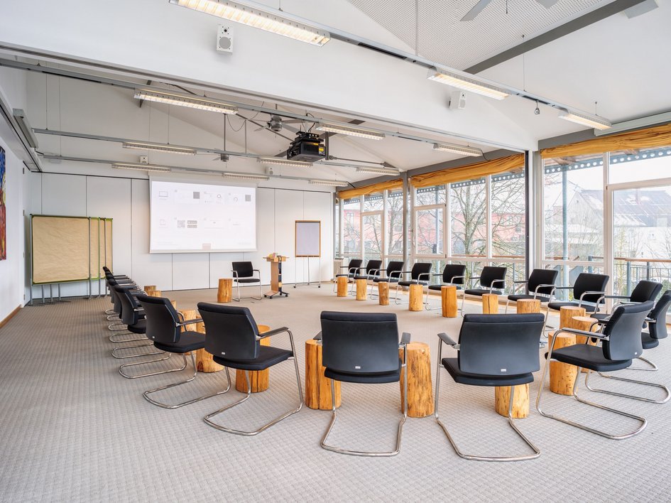 Looking for somewhere for conferences in Bavaria? Large bright conference room with chairs in a circle and wooden stools as tables