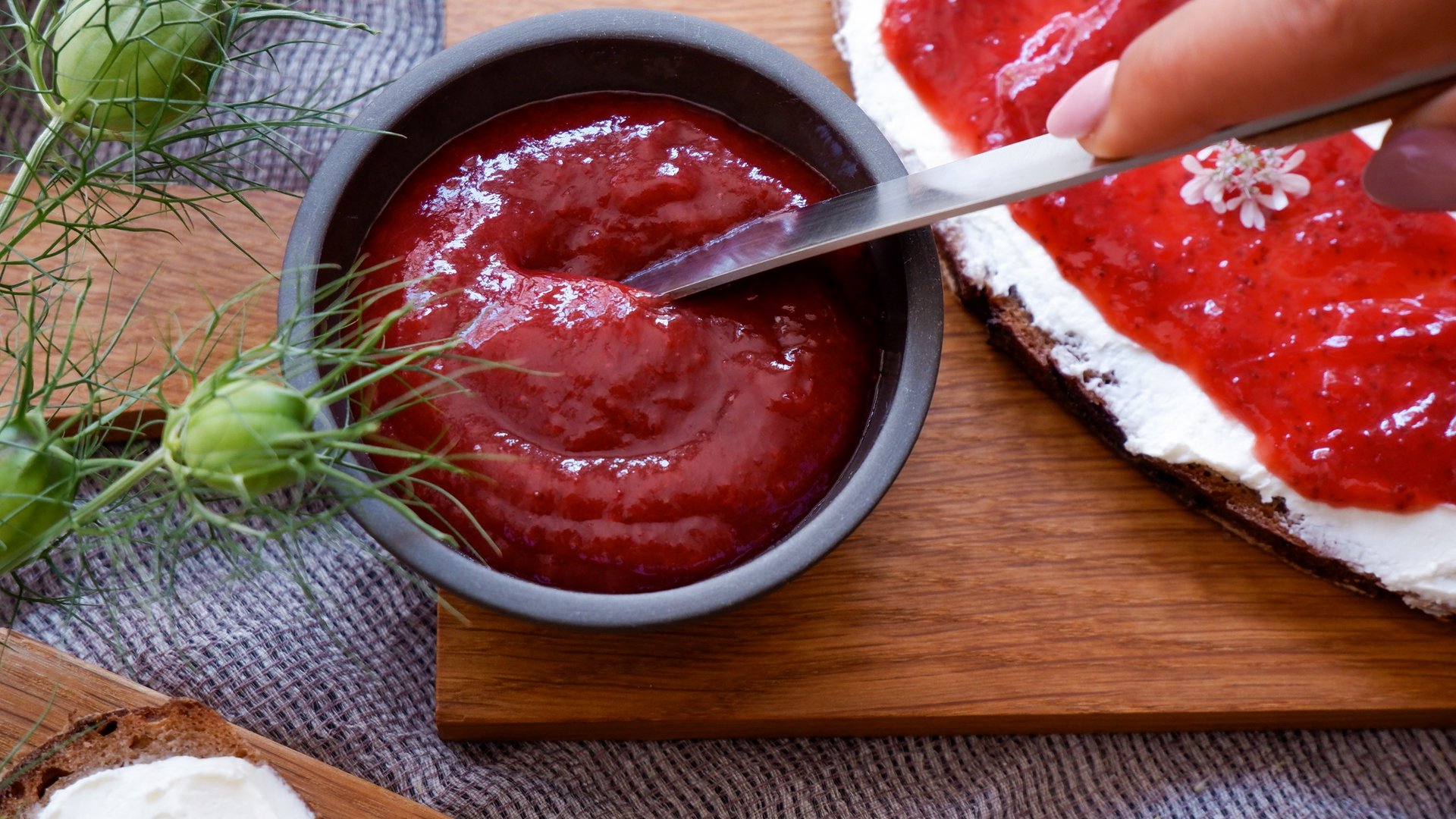 Nachhaltiges Hotel in Bayern mit Hirschenmanufaktur Brot mit Frischkäse und Erdbeermarmelade neben einer Schale Marmelade mit Messer