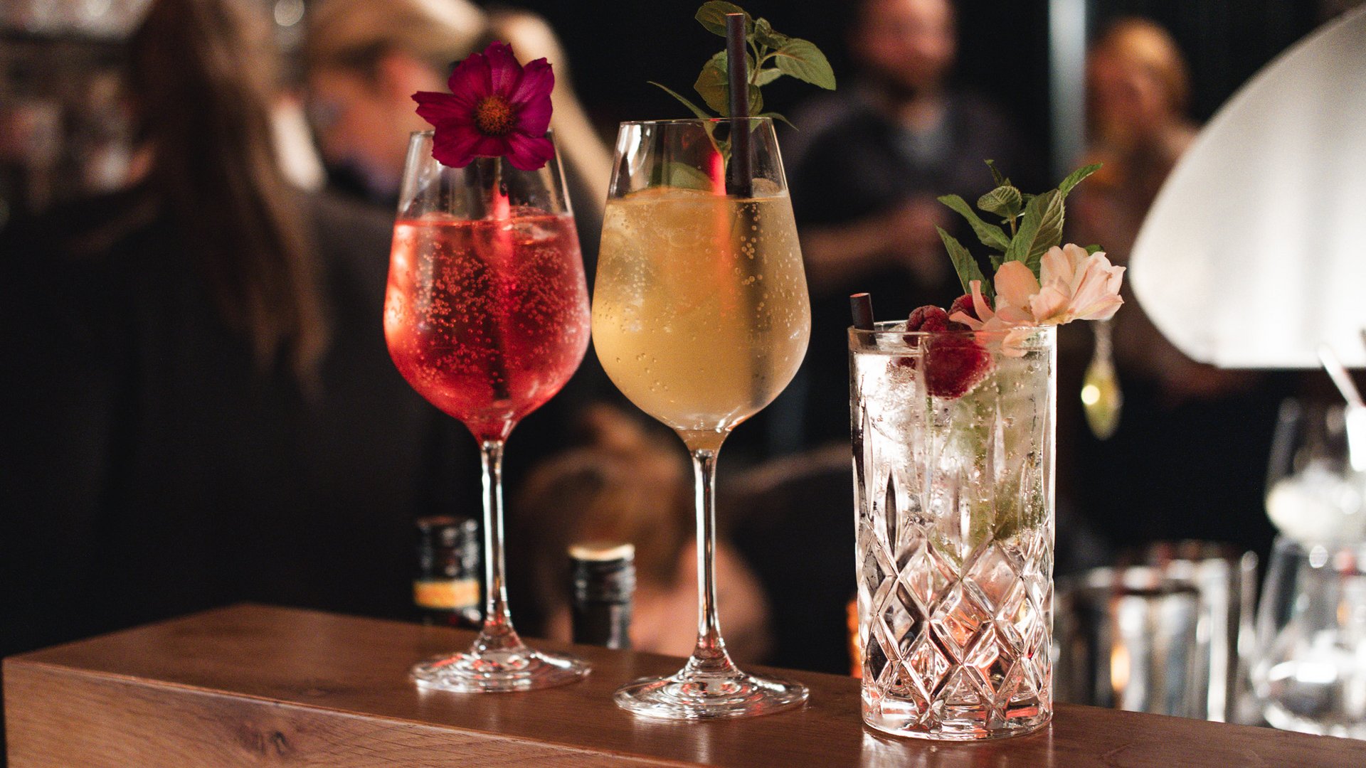 Hirschenblobb: unsere Bar Drei dekorierte Cocktailgläser auf einer Bar mit unscharfem Hintergrund