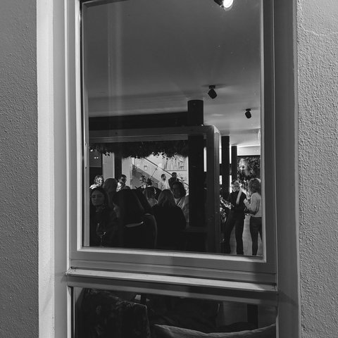 Hirschenblobb: unsere Bar Menschen versammeln sich drinnen bei einer Veranstaltung, gesehen durch ein Fenster