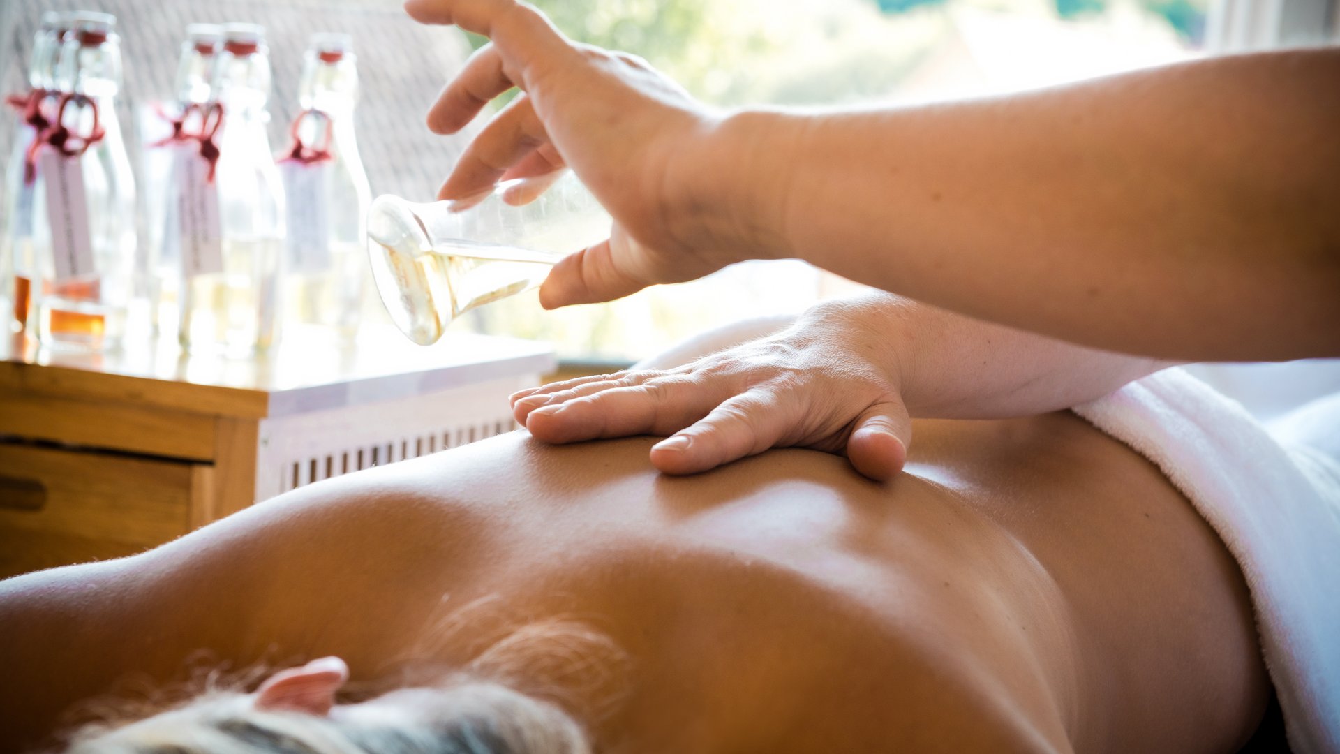 Wellness in der Oberpfalz: Massage & Beauty Person erhält Massageöl auf den Rücken in einem Spa-Umfeld