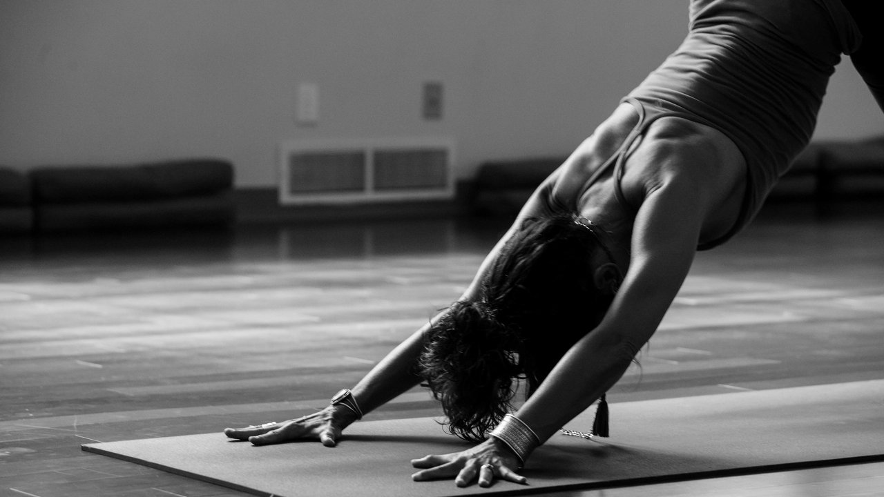 Woman doing yoga pose on mat in a room with wooden floor