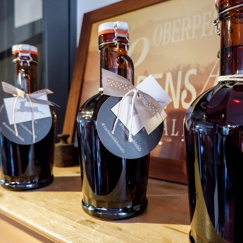 Eco-friendly hotel in Germany with Hirschenmanufaktur Dark glass bottles with decorative labels and bows on wooden shelf