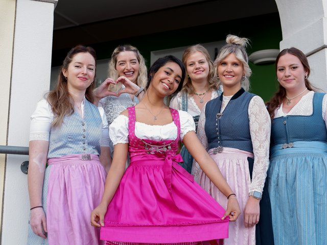 Romantik Hotel Hirschen: Bildergalerie Sechs Frauen in traditionellen Trachten posieren lächelnd vor einem Gebäude