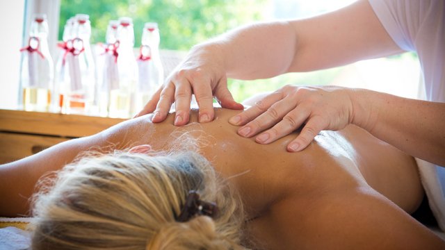 Romantik Hotel Hirschen: Blog Person erhält Rückenmassage in hellem Raum mit Glasflaschen im Hintergrund