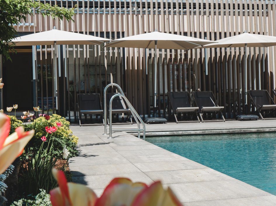 Mental Leadership Retreat Moderner Poolbereich mit Liegestühlen, Sonnenschirmen und blühenden Blumen