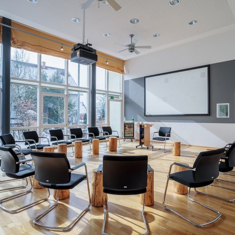Looking for somewhere for conferences in Bavaria? Modern circle of chairs with wooden stools in a bright seminar room