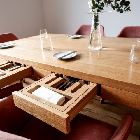 Restaurant in Parsberg: Gourmet genießen Holztisch mit ausziehbarer Besteckschublade und elegant gedecktem Essbereich