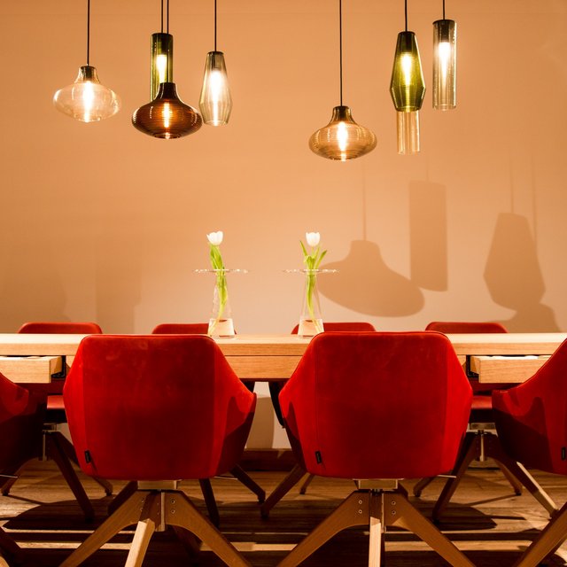 Hochzeitslocation Oberpfalz gesucht? Moderner Essbereich mit roten Stühlen, Holztisch und hängenden Lampen