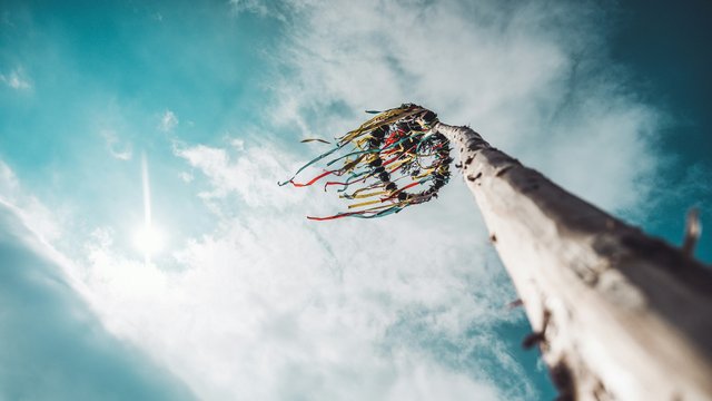 Romantik Hotel Hirschen: Blog Blick nach oben auf einen Maibaum mit bunten Bändern bei bewölktem Himmel