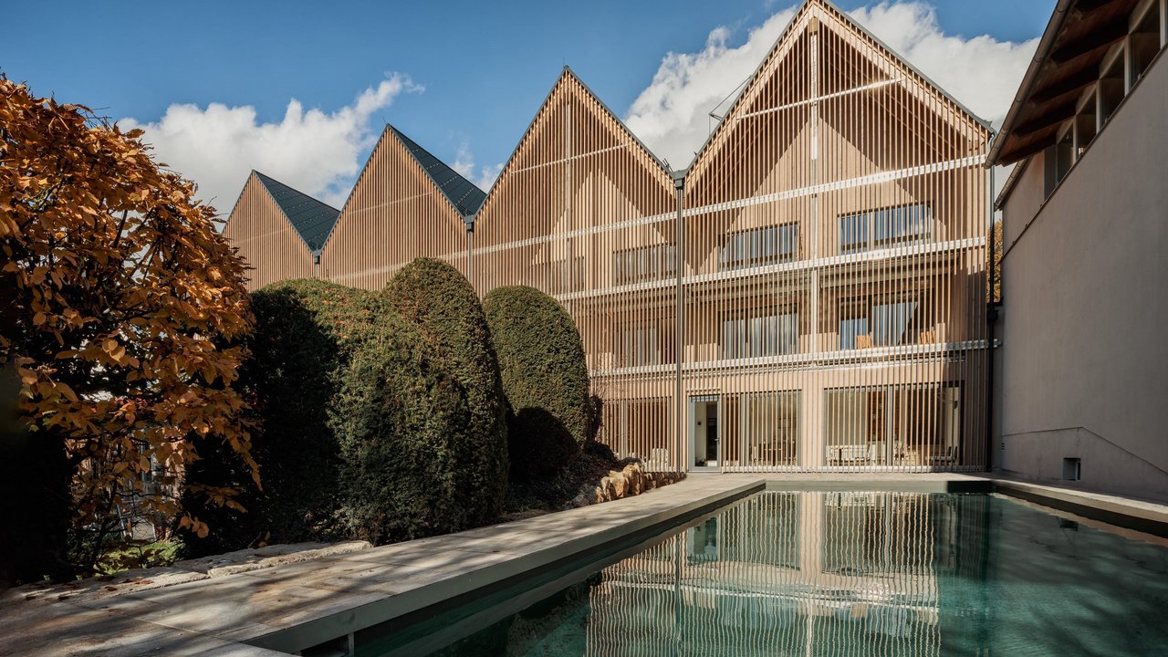 Modern building with wooden facade and pool in garden on sunny day