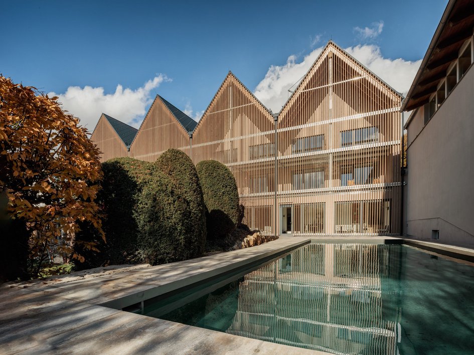 Hotel mit frühem Check-in Modernes Gebäude mit Holzfassade und Schwimmbecken im Garten bei sonnigem Wetter