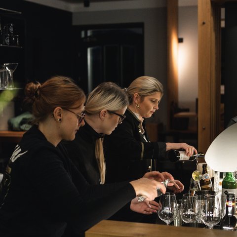 Hirschenblobb: Our bar Three women preparing drinks at a bar counter