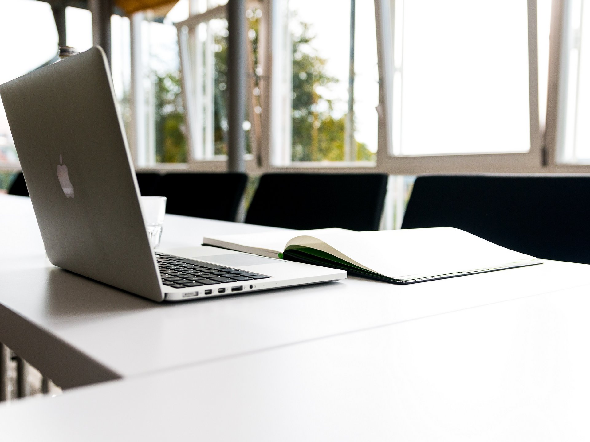 Tagungsräume mit moderner Technik in der Oberpfalz Offener Laptop und Buch auf einem weißen Tisch in einem Besprechungsraum