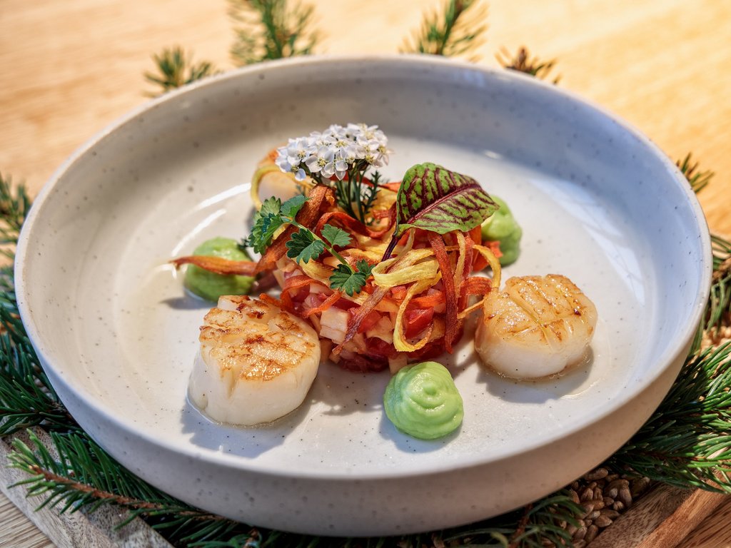 Wellness Seared scallops with vegetables and green cream on a white plate