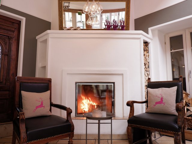 Romantik Hotel Hirschen: Bildergalerie Gemütliche Sitzecke mit Kamin, zwei Sesseln und Dekokissen mit Hirschmotiv