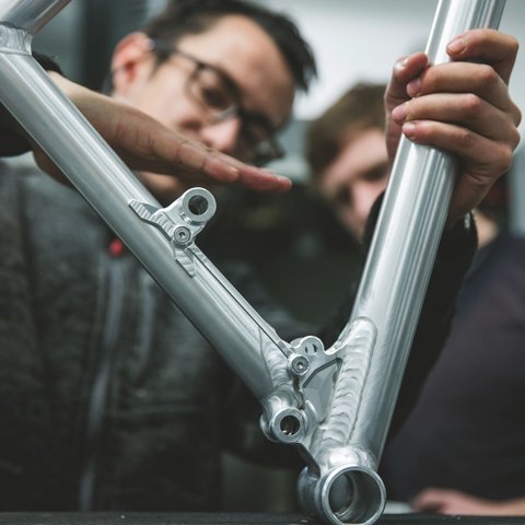 Hotel mit Fahrradverleih in Bayern gesucht? Zwei Männer überprüfen einen glänzenden Aluminium-Rahmen eines Fahrrads