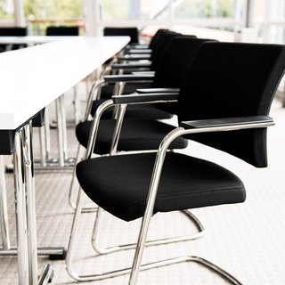 Restaurant in Parsberg: Gourmet genießen Schwarze Bürostühle an weißem Konferenztisch in hellem Raum