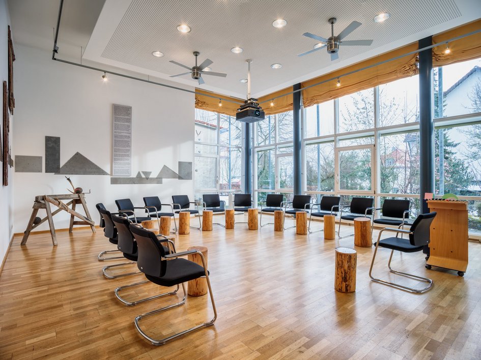 Looking for somewhere for conferences in Bavaria? Conference room with circle of chairs and wooden stools by large windows