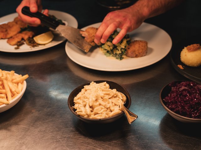 Romantik Hotel Hirschen: Bildergalerie Person richtet traditionelles deutsches Essen auf Tellern an