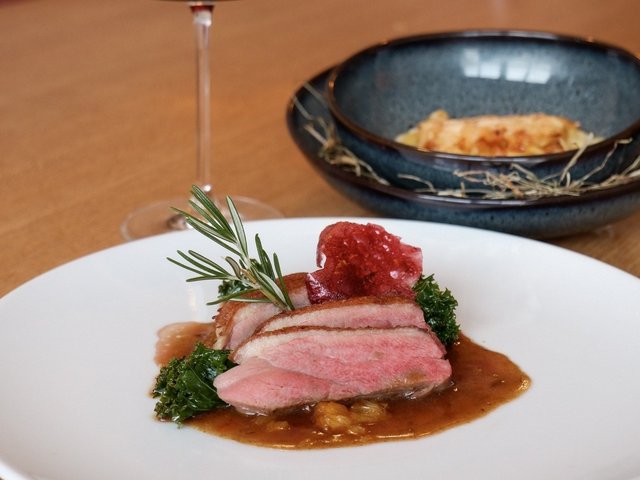 Romantik Hotel Hirschen: Bildergalerie Gedeckter Tisch mit Glas Rotwein und angerichtetem Fleischgericht