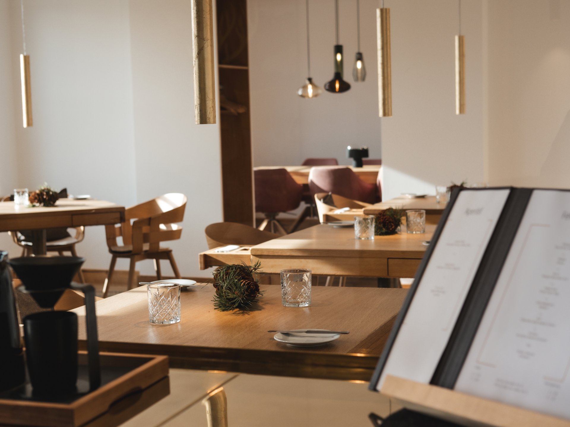 Wellnesshotel Parsberg – Romantik Hotel Hirschen Modernes Restaurant mit Holz Tischen, Gläsern und Menü auf Halterung