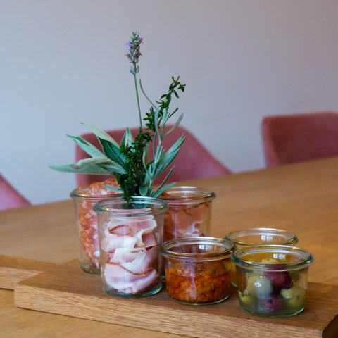 Gasthof Parsberg: Ein Gruß an den guten Geschmack Holzbrett mit Glasgefäßen gefüllt mit Wurst, Kräutern, Oliven und Dips