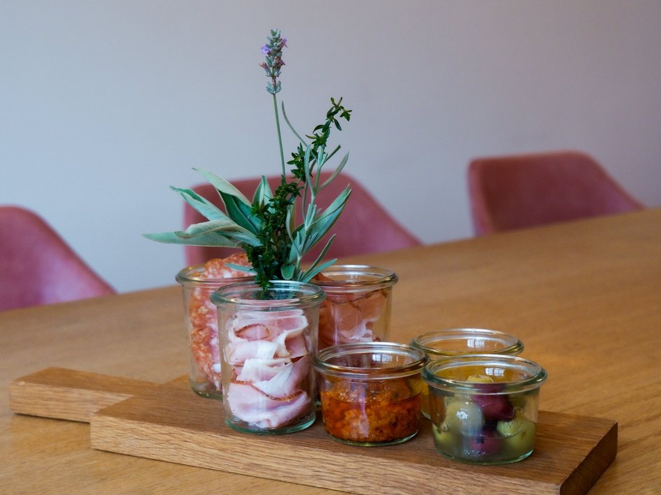 Gasthof Parsberg: Ein Gruß an den guten Geschmack Holzbrett mit Glasgefäßen gefüllt mit Wurst, Kräutern, Oliven und Dips