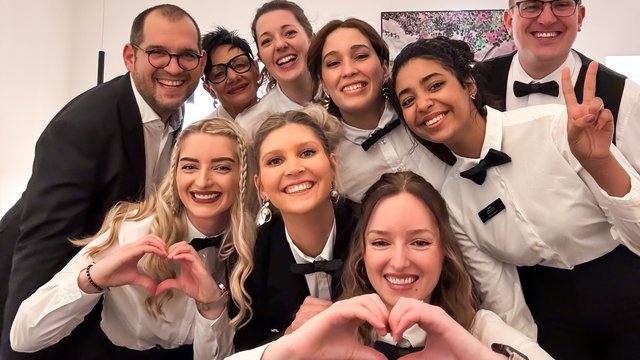 Hochzeitslocation Oberpfalz gesucht? Lächelndes Servicepersonal in Uniform macht Herz- und Friedenszeichen