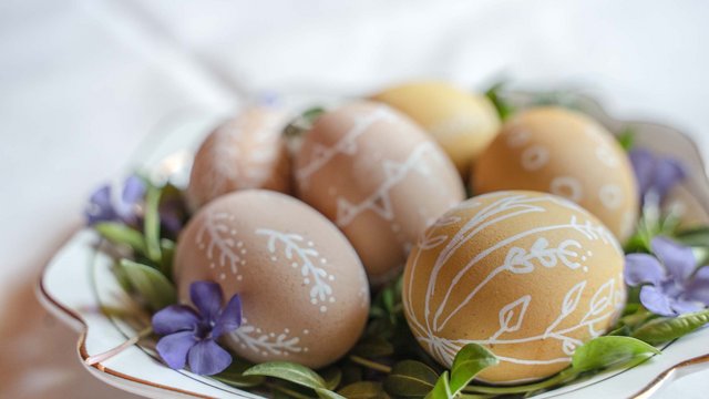 Romantik Hotel Hirschen: Blog Braune Ostereier mit weißen Mustern auf grünen Blättern und lila Blumen