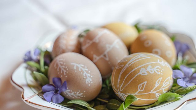 Romantik Hotel Hirschen: Blog Braune Ostereier mit weißen Mustern auf grünen Blättern und lila Blumen