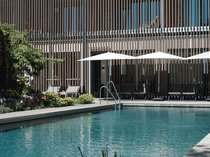 Workation Moderner Pool mit Liegestühlen und Sonnenschirmen vor vertäfeltem Gebäude