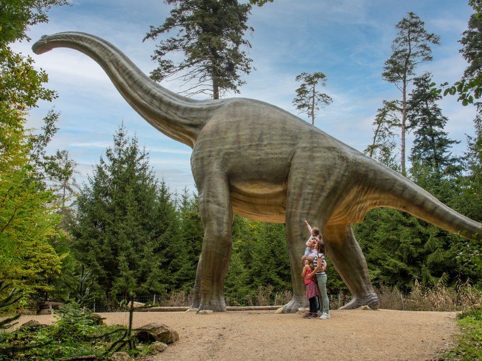 Wandern in der Oberpfalz: Aktiv in der Natur Familienszene vor großem Dinosauriermodell im Waldpark