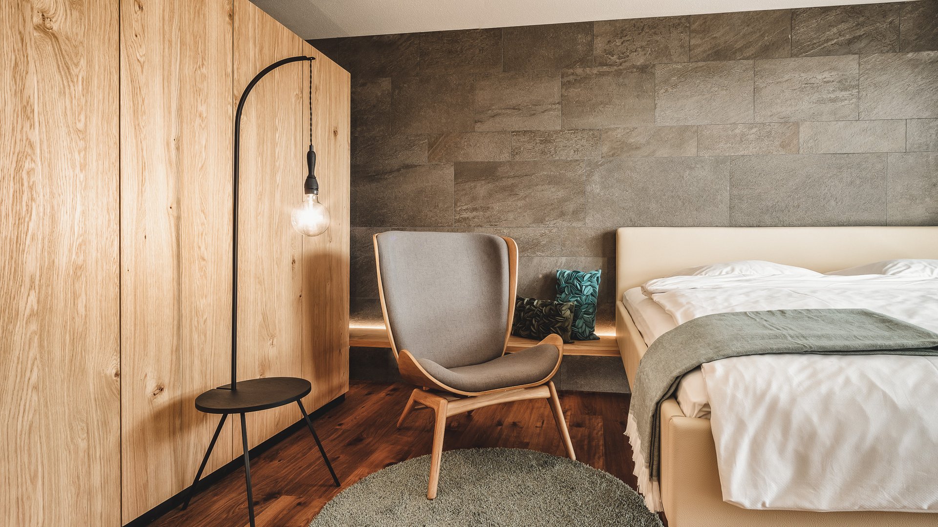 Hotel Oberpfalz: Urlaubsluft schnuppern! Modern eingerichtetes Schlafzimmer mit grauem Stuhl und Holzschrank