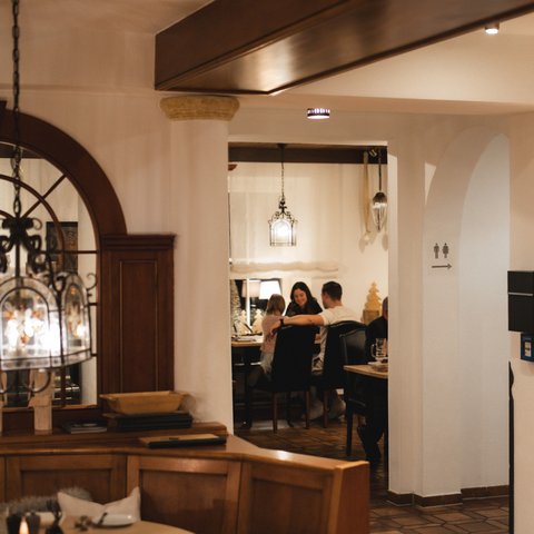 Romantik Hotel Hirschen: Gastgeber & Werte Gemütliches Restaurant mit Holzdeko und Gästen am Esstisch im Hintergrund